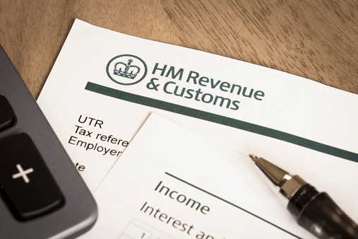 hm revenue and customs tax return form, a pen and calculator on a desk